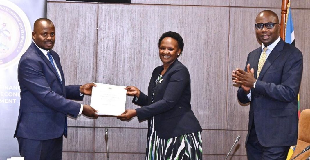 Minister Shartsi Kuteesa Takes Over Uganda’s Microfinance Portfolio as Kasolo Hands Over Outgoing Minister Haruna Kasolo hands over microfinance portfolio files to New State Minister for Finance Shartsi Kuteesa Musherure during the formal handover ceremony at the Ministry of Finance, Planning and Economic Development.